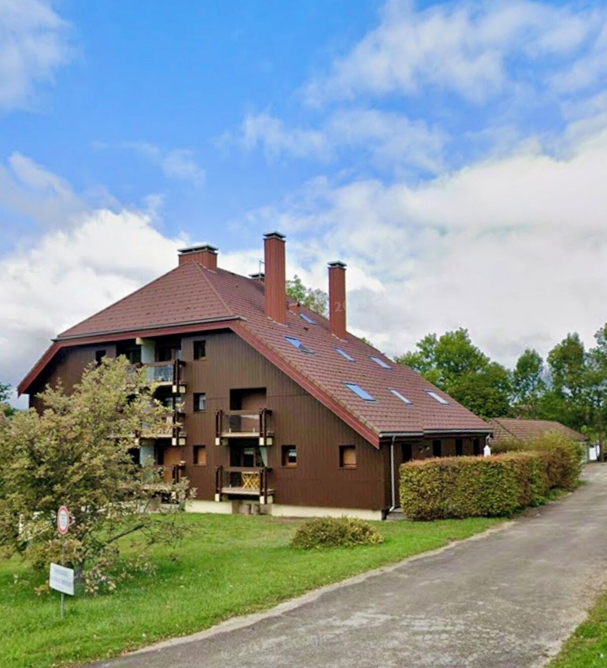 A two-story building with a sloped roof, multiple chimneys, and a small porch area.