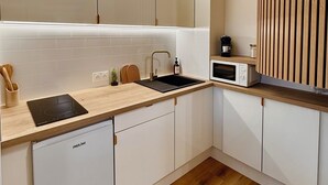 Una cocina moderna con armarios blancos, encimera de madera, lavavajillas empotrado y microondas.