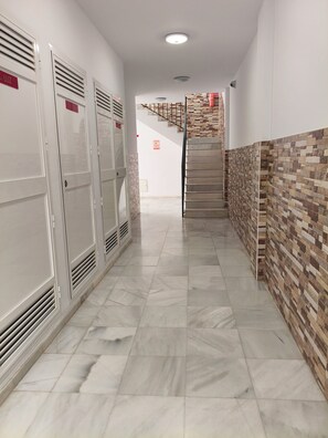 Ein Korridor mit Schließfächern, gefliestem Boden und einer Treppe mit einer Wandverkleidung.