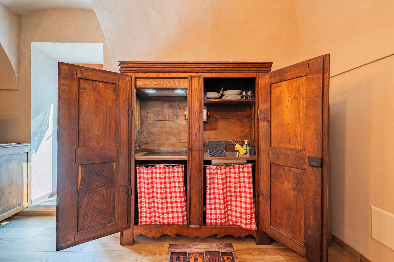 Ein Holzkabinett mit geöffneten Türen, das Regale und ein Waschbecken zeigt.