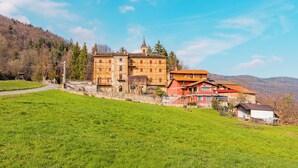 Un grand immeuble à étages, doté d’une tour imposante, situé sur une colline verdoyante sous un ciel dégagé.