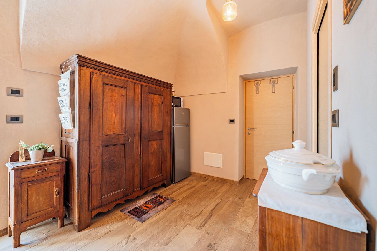 Une cuisine avec des meubles de rangement en bois, un réfrigérateur, une cuisinière et une petite table d’appoint sur laquelle est posée une plante.