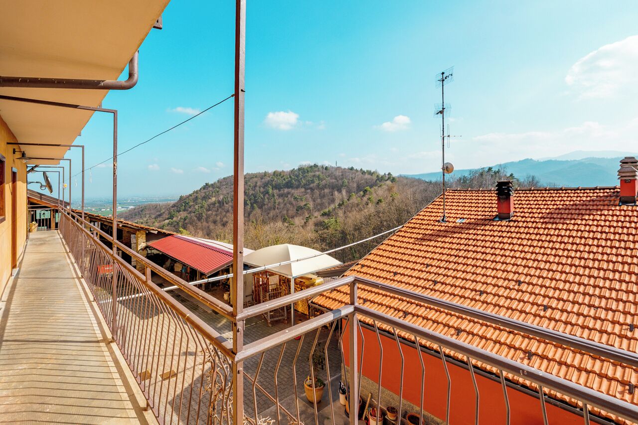 Ein Balkon mit Blick auf eine gebirgige Landschaft, ein Ziegeldach und ein Holzdeck.