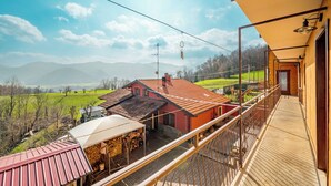 Ein Balkon mit Blick auf ein rotes Gebäude und ein grünes Feld.
