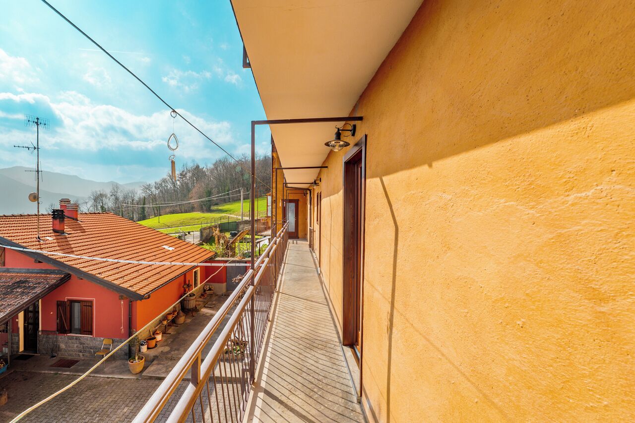A balcony with a view of a red-roofed building, a paved walkway, and a clear sky.
