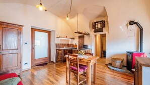 Ein gemütliches Interieur mit einem Holzespeisetisch, Stühlen, einer Küchenzeile und einem sichtbaren Kamin.