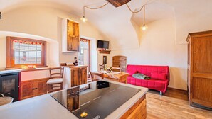 Eine Küche mit Herd, Holzschränken und einem Essbereich mit einem roten Sofa.