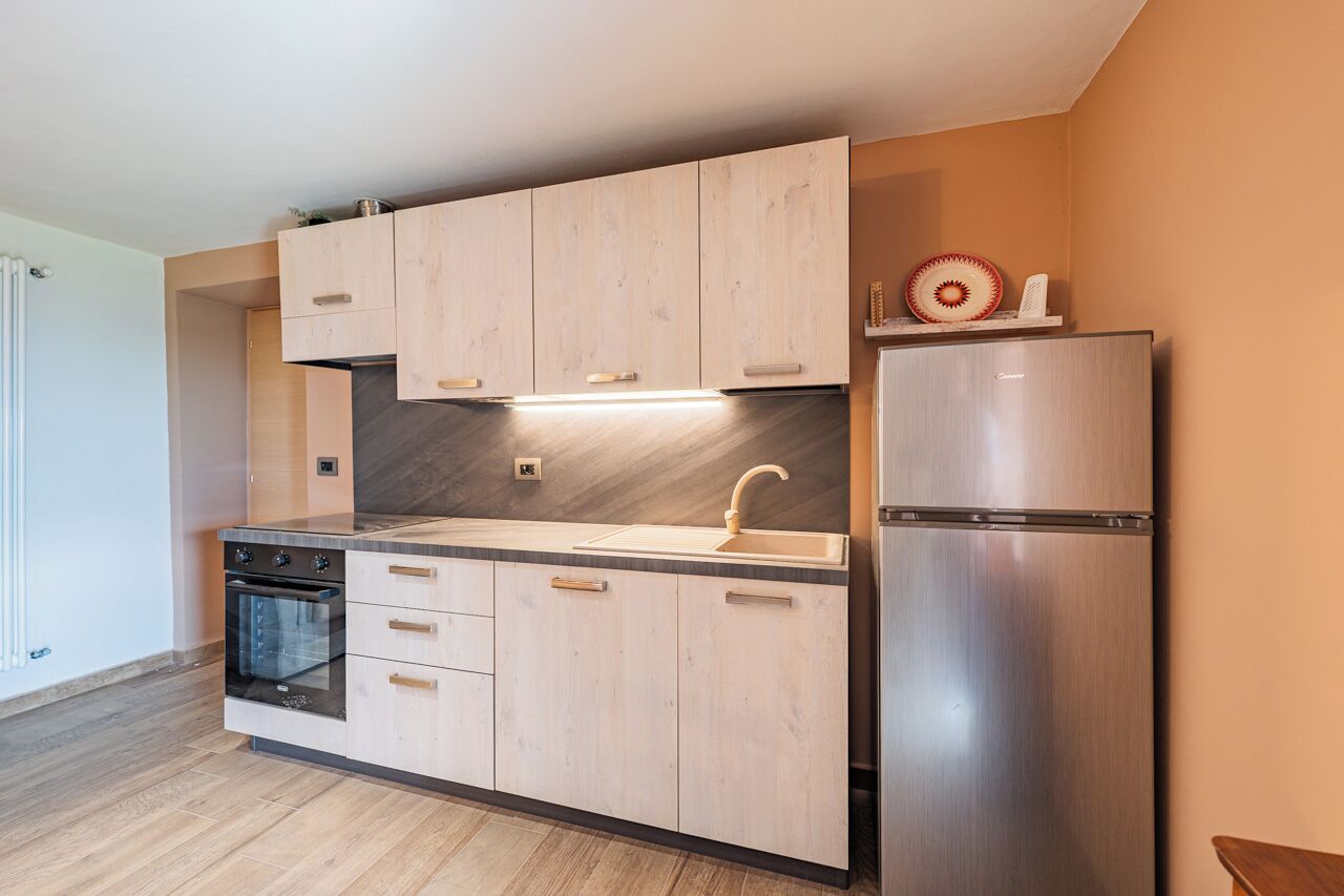 Eine moderne Küche mit Holzausstattung, einem Edelstahlkühlschrank und einem eingebauten Backofen.