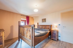 Une chambre à coucher avec un lit en bois, une table de chevet, une porte et un luminaire au plafond.