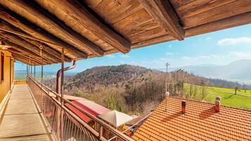 Ein hölzerner Balkon mit Blick auf eine hügelige Landschaft.