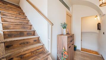 Een houten trap die uitkomt op een plateau met een houten kast en een bloevas.