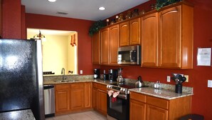 A kitchen with wooden cabinets, stainless steel appliances, and a granite countertop. - All-suite south-facing pool home - attractions/shopping/dining minutes away! (Kissimmee)