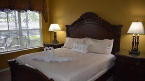 A neatly made bed with a decorative swan towel, two bedside lamps, and a view of the outdoors through a window with blinds. - All-suite south-facing pool home - attractions/shopping/dining minutes away! (Kissimmee)
