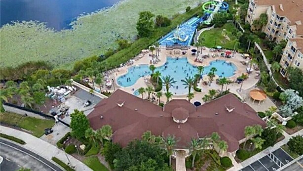 An aerial view of a resort with multiple swimming pools, a water park, and a central building with a red roof. - All-suite south-facing pool home - attractions/shopping/dining minutes away! (Kissimmee)