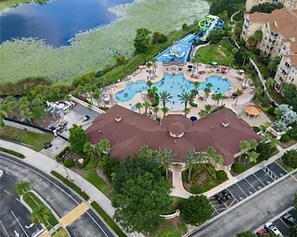 Luchtbeeld van een resort met meerdere zwembaden, een waterpark en een centraal gebouw met een rood dak.