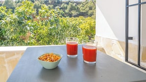 A balcony with a table, two glasses of red liquid, and a bowl of nuts. - Villa Alonso Linares Nerja by Ruralidays (Málaga)