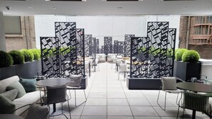 A modern lounge area with sofas, tables, and chairs, separated by black and white patterned partitions. - Luxury NYC Stay Near Fifth Ave, Central Park & Rockefeller Center Studio Plus (New York City)