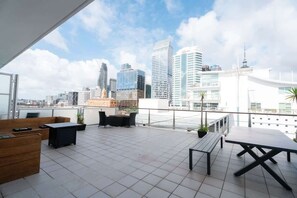 A rooftop terrace with outdoor furniture, a city skyline view, and modern buildings in the background. - Princes Wharf Harbour View Studio (Auckland Central)