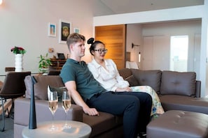 A modern living room with a sofa, a small round table with a glass, and a potted plant. - Princes Wharf Penthouse (Auckland Central)