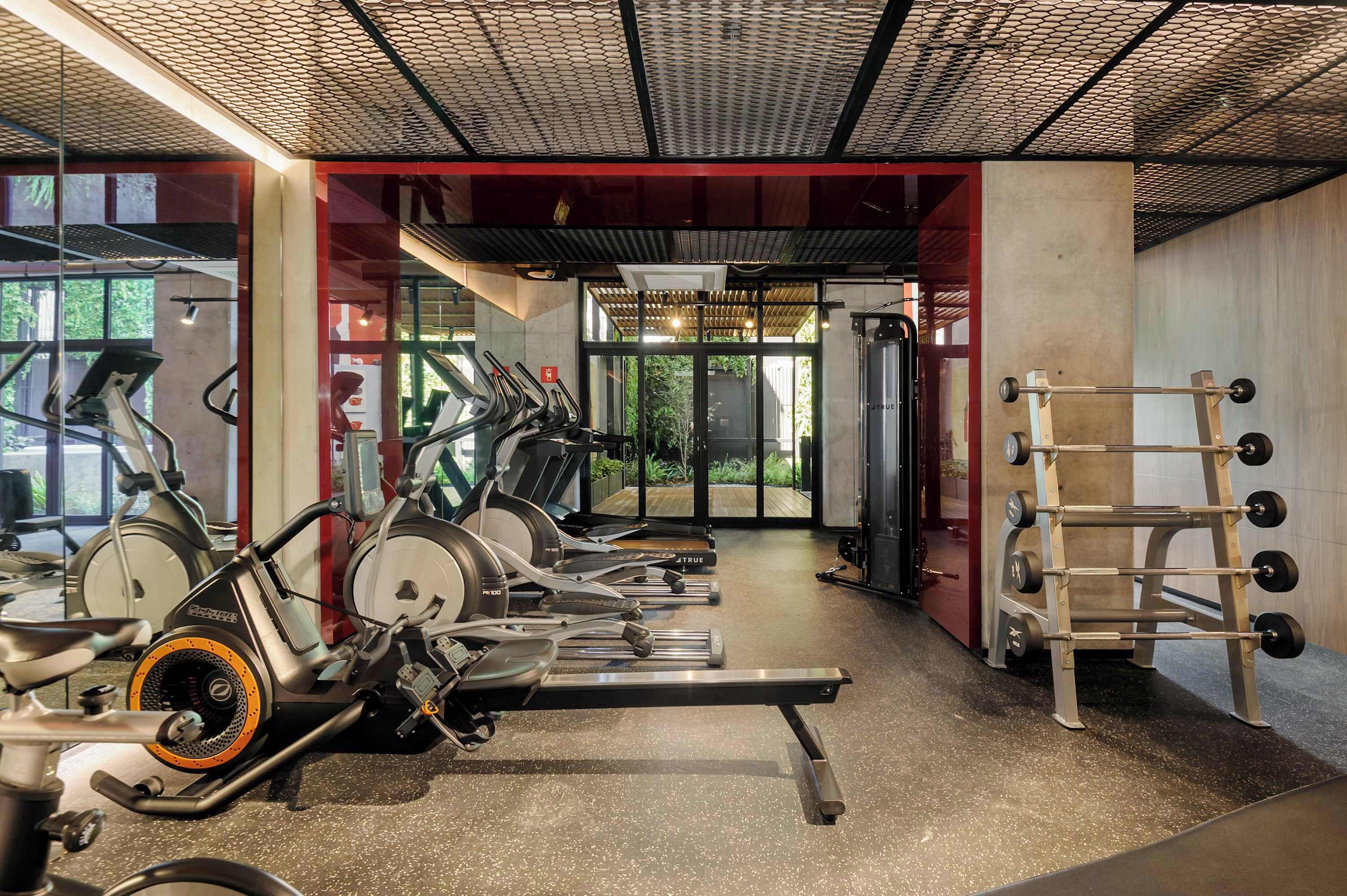 A gym with stationary bikes, treadmills, and a weight rack.