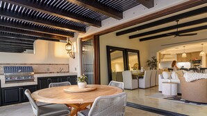 Una cocina moderna con una mesa y sillas de madera, una parrilla empotrada y un ventanal grande.