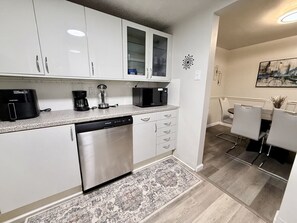 A modern kitchen with white cabinets, a dishwasher, a coffee maker, and a microwave. - Wonderful stylish 2 King bed 1.5 bath home (Pittsburgh)