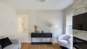 Una sala de estar con un sofá, una consola, una lámpara y una chimenea.