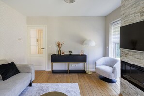 Ein Wohnzimmer mit Sofa, Beistelltisch, Lampe und Kamin.