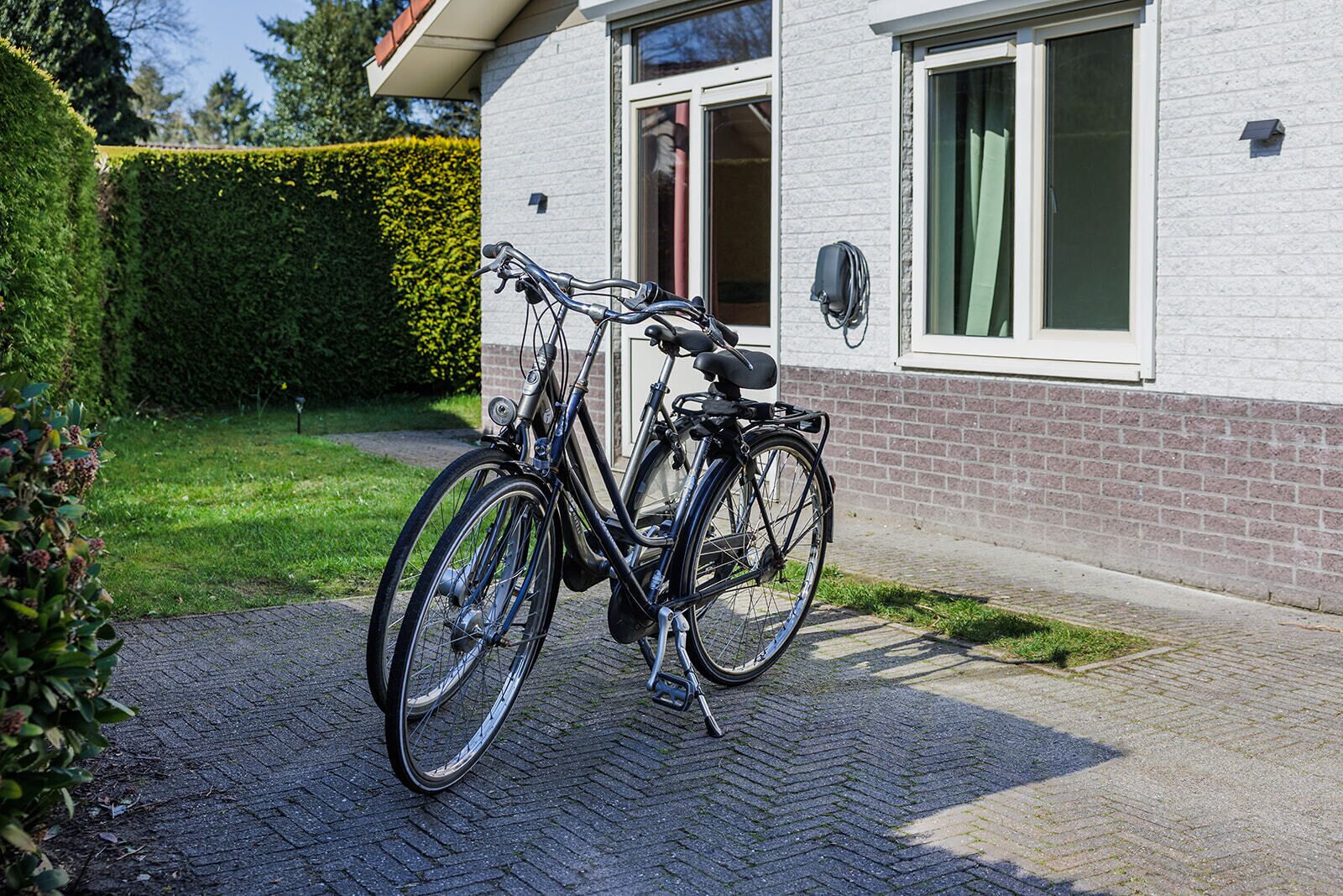 Een fiets geparkeerd voor een gebouw met een bakstenen gevel en een raam met gordijnen.