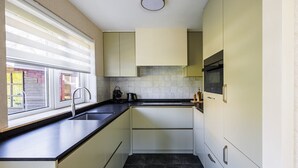 Cocina pequeña con ventana, un lavamanos, estufa y armarios.