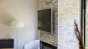 Una sala de estar moderna con chimenea, televisor montado y una lámpara de pie decorativa.