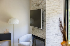 Ein modernes Wohnzimmer mit Kamin, Wandfernseher und einer dekorativen Stehlampe.