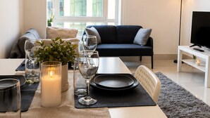 Un salon moderne comprenant un coin repas aménagé pour prendre un repas, un canapé, un téléviseur et une fenêtre offrant une vue agréable.