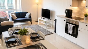 Un appartement moderne comprenant un coin repas, une cuisine, un salon et une grande fenêtre.