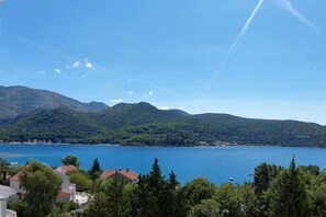 Eine Küstenlandschaft mit freiem Blick auf einen See, Hügel und einige Gebäude im Vordergrund.