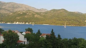 Une vue côtière avec des montagnes, une étendue d’eau et des bâtiments au premier plan.