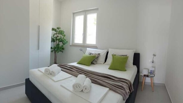 Une chambre d’hôtel moderne avec un lit, des oreillers, une petite table et une fenêtre.