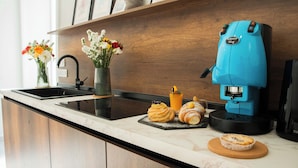 Una encimera de cocina con una cafetera, un florero con flores y pasteles.