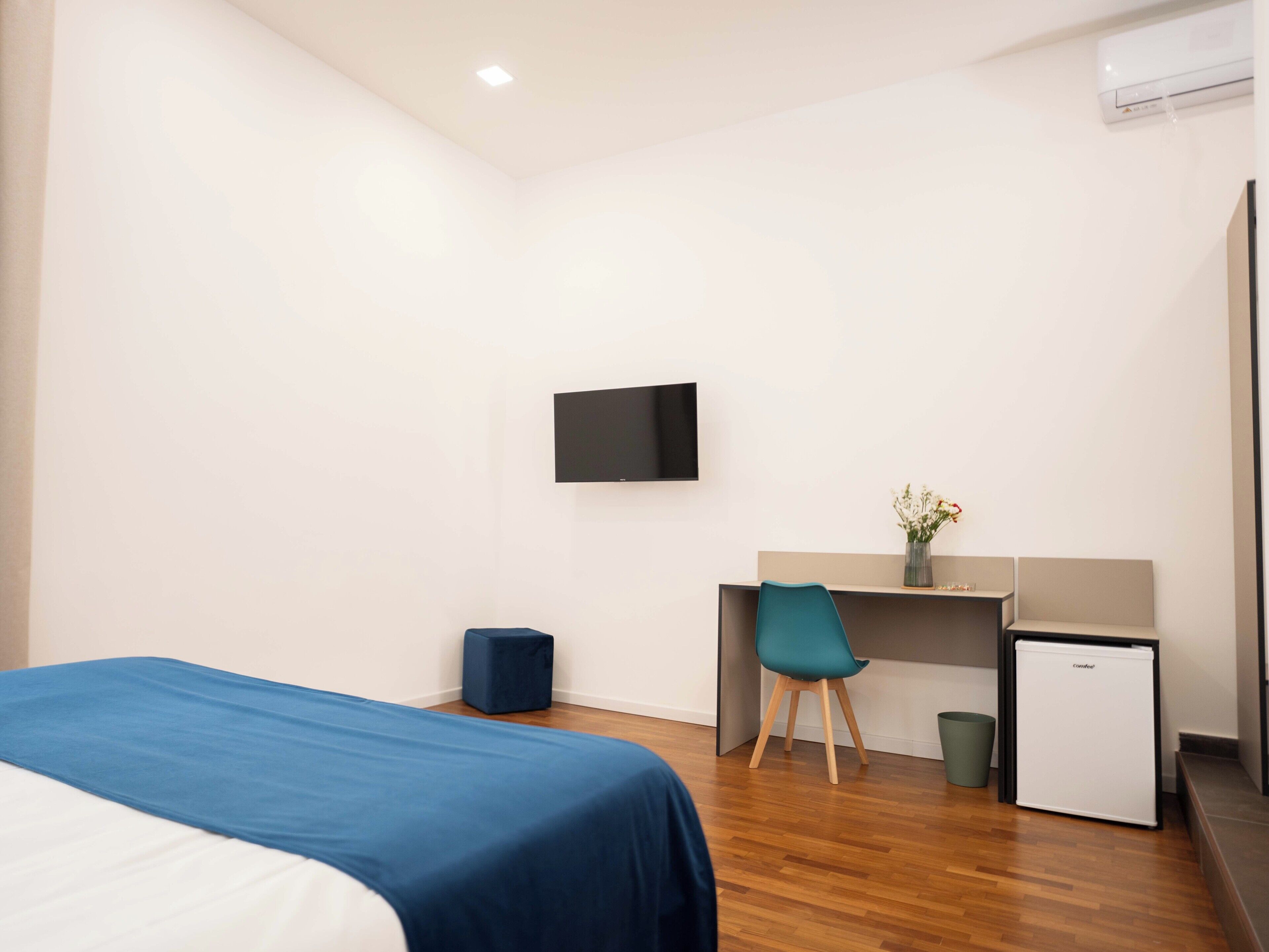Une chambre d’hôtel comprenant un lit, un bureau avec une chaise, une télévision et un petit réfrigérateur.