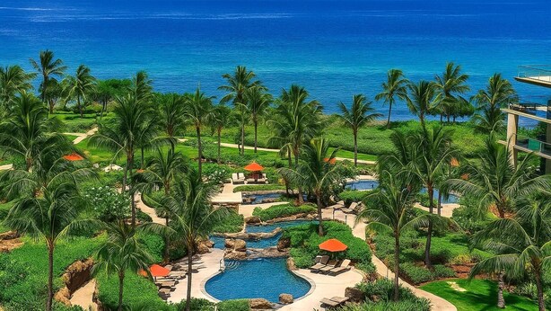 Ein Resort mit Pool, Palmen und Meerblick.