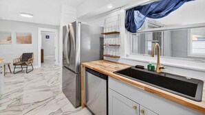 Eine moderne Küche mit einem Edelstahl-Kühlschrank, einer Holz Arbeitsplatte und einem schwarzen Spülbecken.