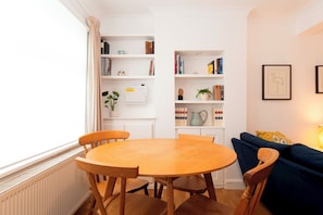 A room with a round wooden table, four chairs, a bookshelf, a sofa, and a radiator. - Charming 2BR Cottage in Richmond, 20 mins C London - Pass the Keys (Richmond)