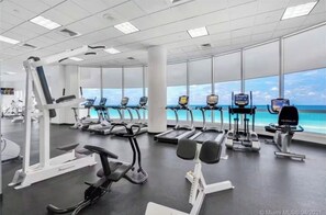 A gym with various exercise machines, large windows, and a view of the ocean. - Perfect luxury Oceanfront 1BA 1.5BA in Miami Beach (Miami Beach)