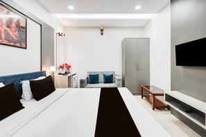 A modern hotel room with a large bed, a sofa, a TV, and a wardrobe.