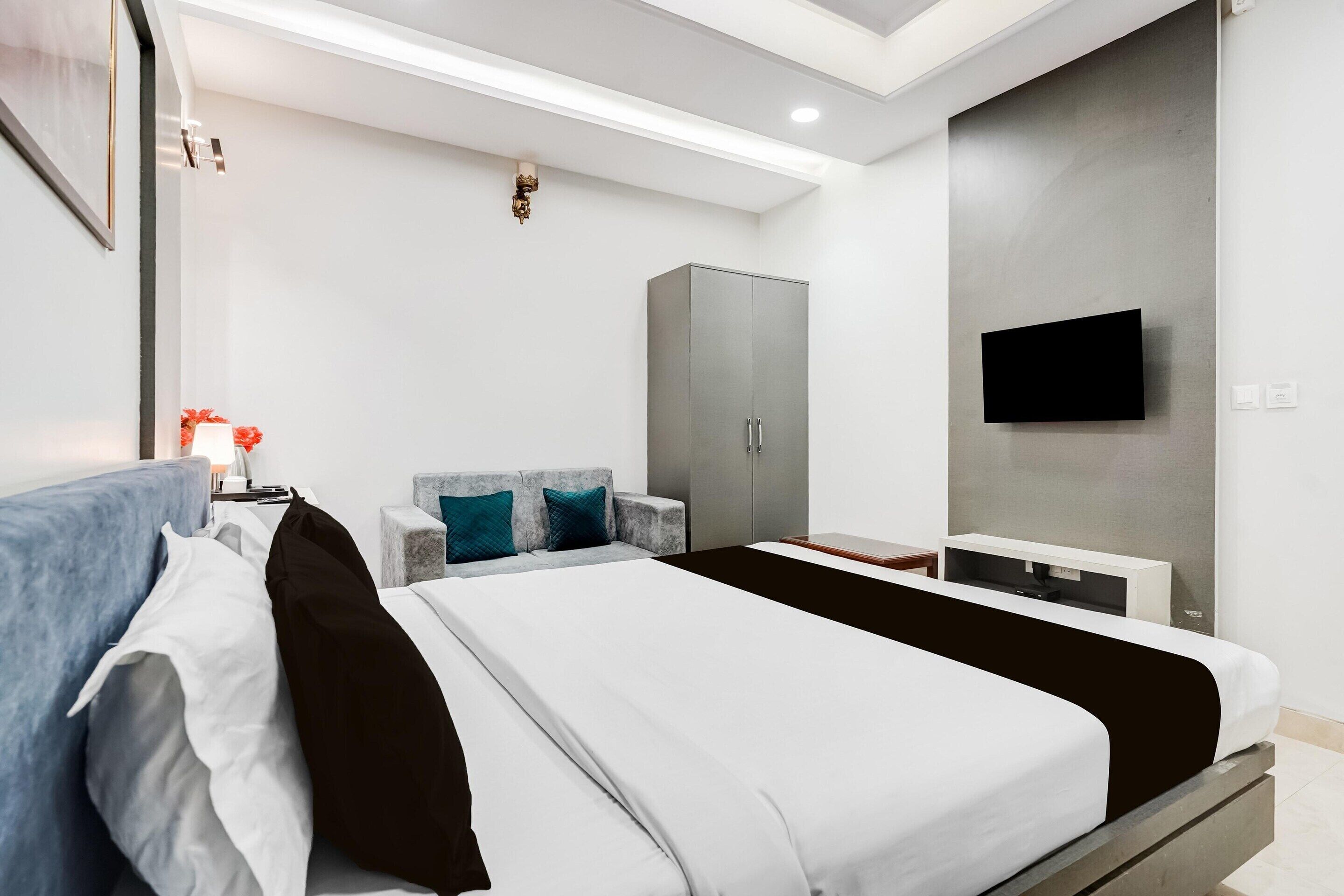 Una camera d'albergo moderna con un letto, un armadio, una televisione e una scrivania.