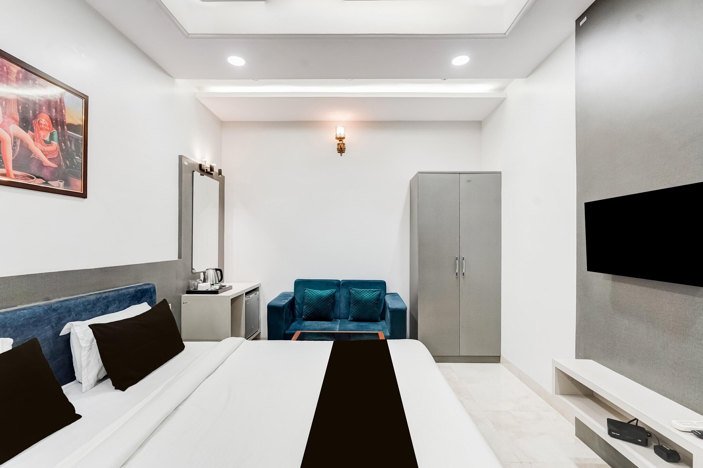 Une chambre d’hôtel équipée d’un lit, d’un canapé, d’une télévision, d’une armoire et d’un bureau avec une bouilloire.
