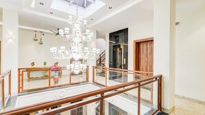 A multi-level interior with a grand chandelier, a staircase, and a wooden door.