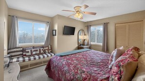 A bedroom with a bed, a window seat, a ceiling fan, a TV, and a wardrobe. - Above the Clouds Views, Fireplace, Near Ski Resort (Beech Mountain)
