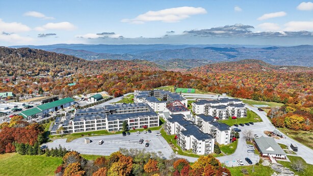 A residential area with apartment buildings, a parking lot, and a view of the surrounding hills. - Above the Clouds Views, Fireplace, Near Ski Resort (Beech Mountain)