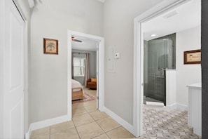 A hallway with a bed, a shower, and a door leading to another room. - Coconut Villa Suite 2 (Redington Shores)